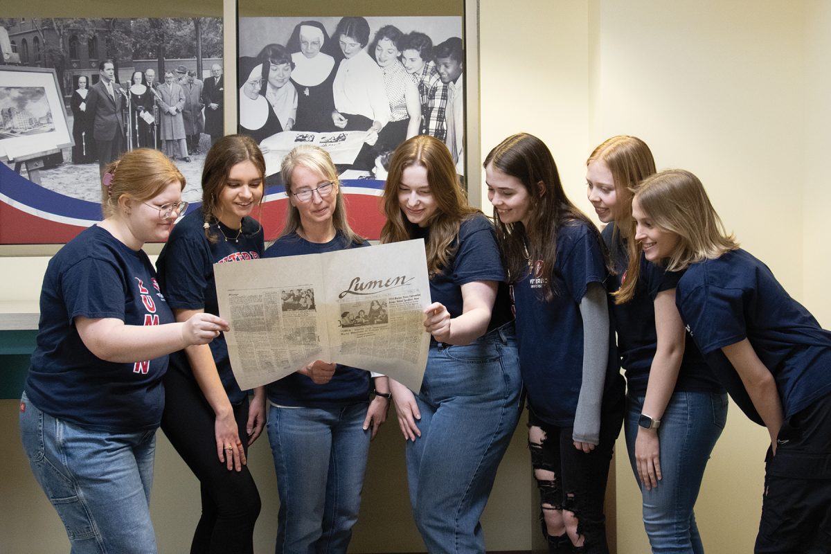 Current Lumen staff members recreate the photo from 1954 that appears on the wall behind them. From left to right: Heidi Kloostra, Megan Carey, Jackie Herbers, Lindsay Koza, Ava Stoekly, Olivia Gochenaur, and Helen Riddle. 