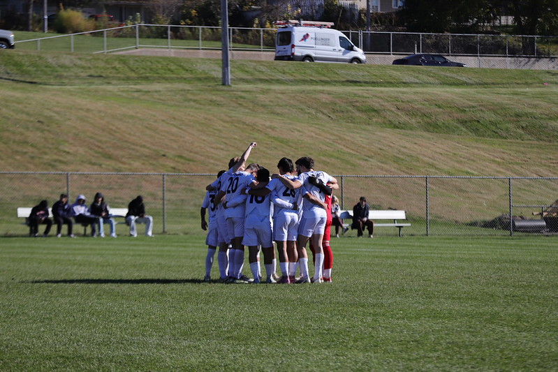 The men’s soccer team huddles together 